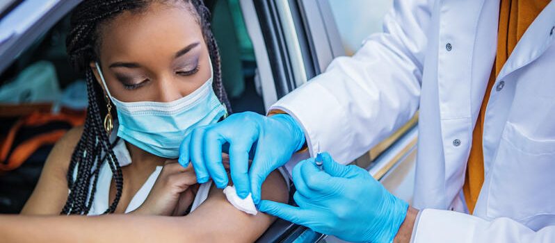 Covid-19 Vaccination administered by a black doctor at a drive-in medical facility Covid-19 Vaccination administered at a drive-in medical facility by a black medical professional whilst respecting the lockdown due to the corona virus outbreak