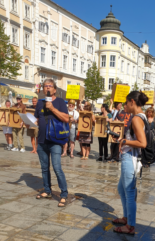 Heinz Zauner steht mit Mikrofon in der Hand auf dem Linzer Hauptplatz. Er hält gerade eine Rede