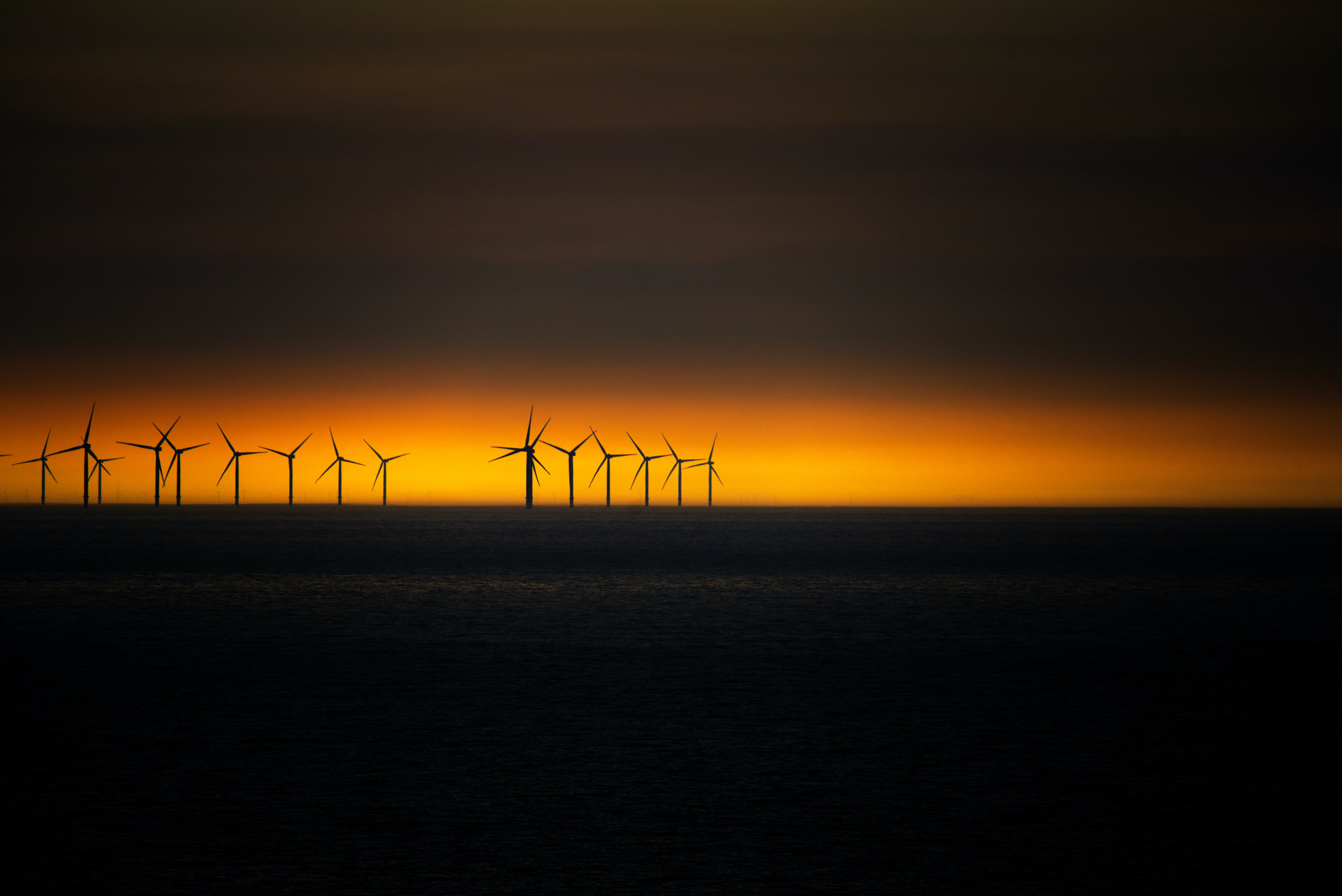 Weit weg am Horizont sieht man eine Reihe von Windrädern