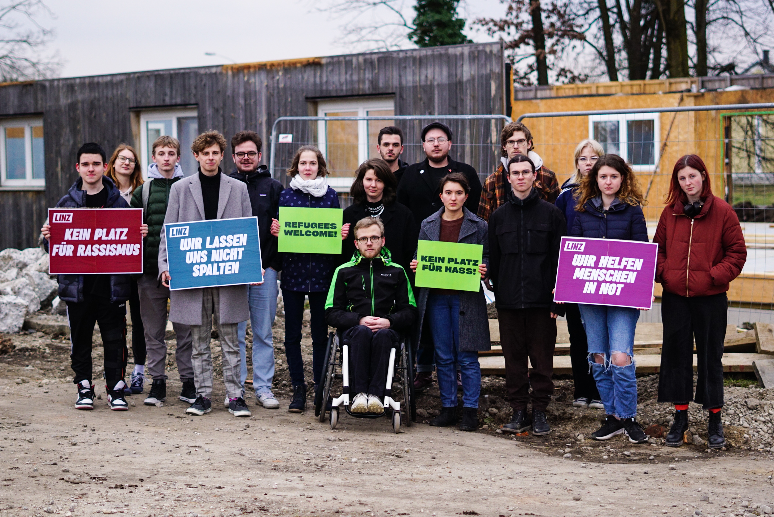 Eine Gruppe an Menschen hält antirassistische Schilder hoch