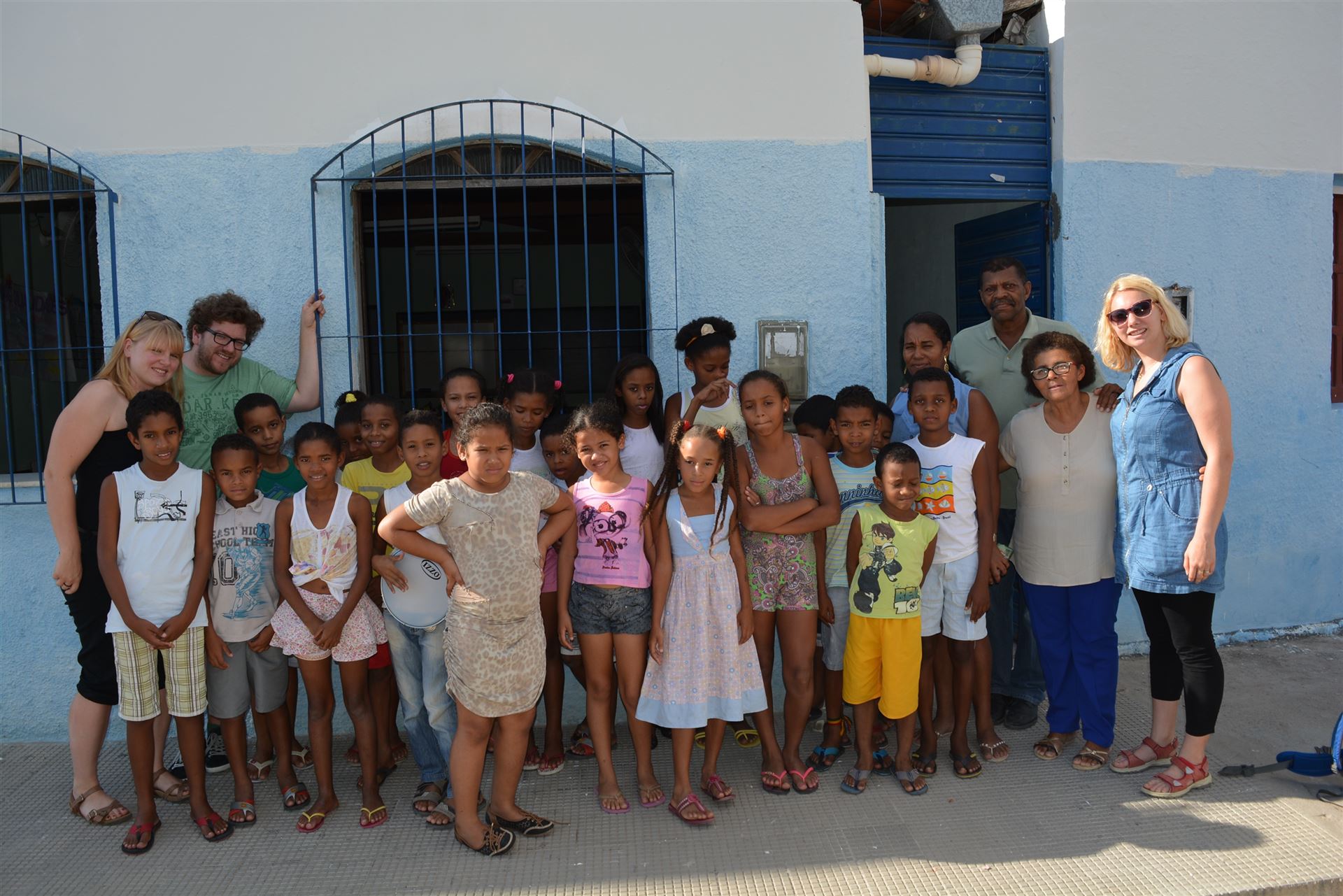 Es ist ein Gruppenfoto. In der Mitte stehen viele Kinder und links und Rechts Erwachsene.