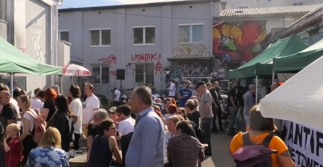 eine Menschenmenge im alten Schlachthof in Wels. Sie sind auf einem Fest. Es sind Bänke und Schirme aufgestellt