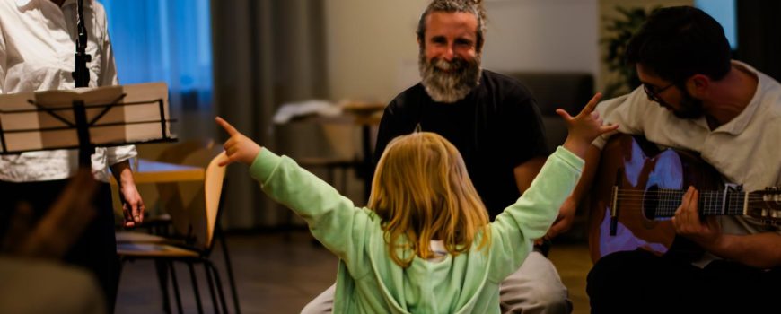 202604_Start_BweB_CF Mehr Sichtbarkeit für unsichtbare Krankheiten: Alma macht das Y-Zeichen, im Hintergrund spielt die Band das Lied: Beat of Hope.