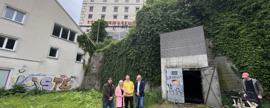 FMR Rundgang foto Der Veranstalter Thomas Philipp Thomas, die Kulturstadträtin Doris Lang-Mayerhofer, und Julius Stieber, Lorenz Homolka sowie ausstellende Künstler*innen des FMR 26 stehen vor dem Schlossbergstollen, der ebenfalls für Kunstinstallationen genutzt wird.